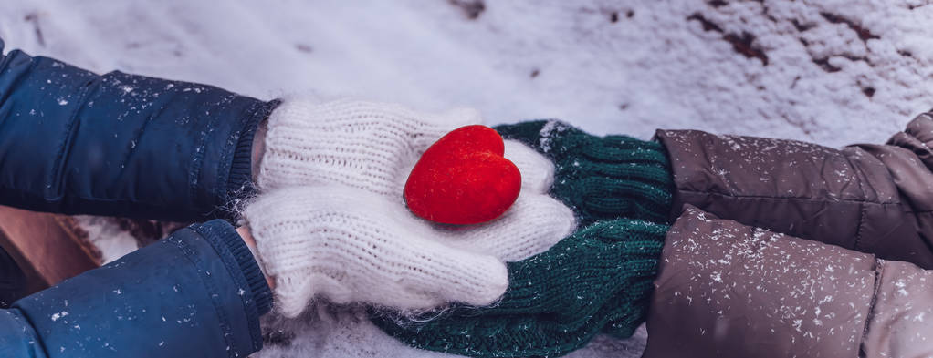Mani in guanti tenendo il cuore primo piano su sfondo neve invernale. Tonica
. - Foto, immagini