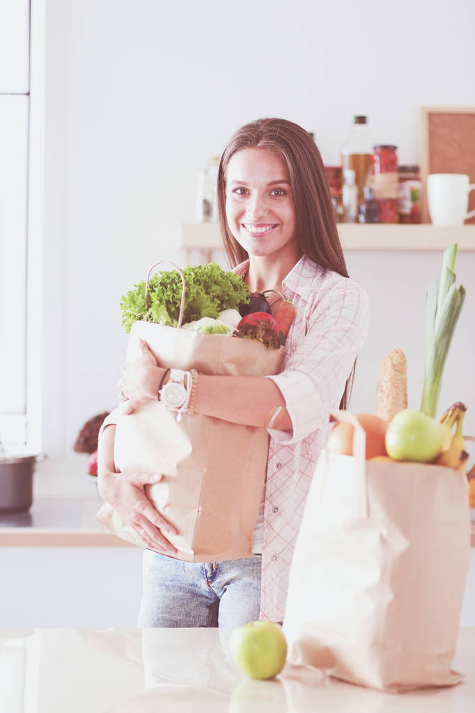 Młoda kobieta trzyma torbę na zakupy z warzywami. Młoda kobieta - Zdjęcie, obraz