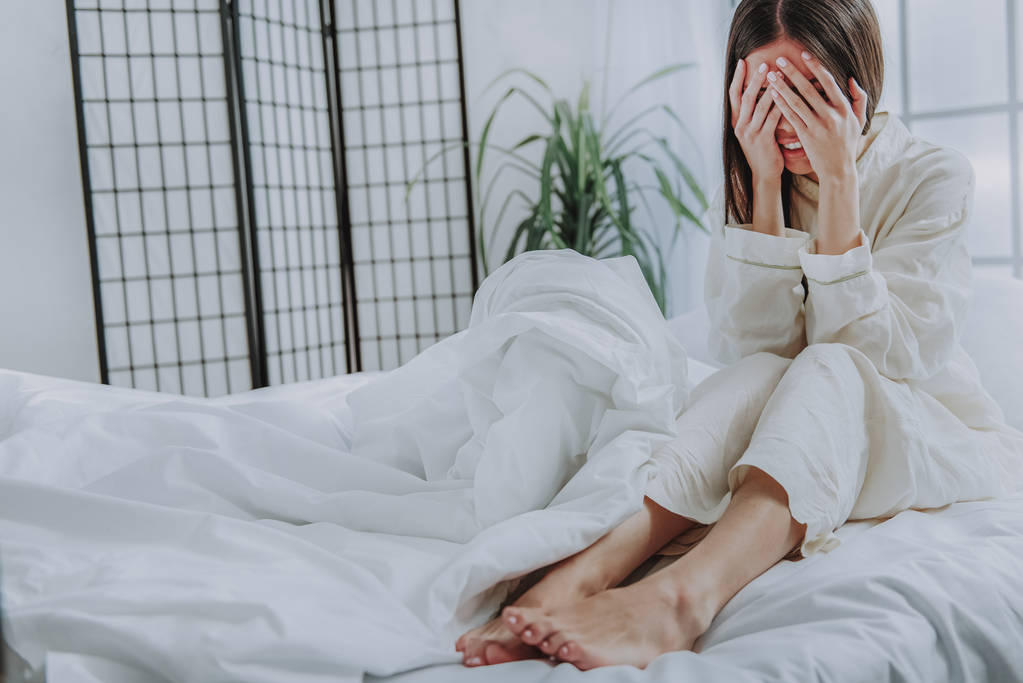 Deprimido asiático mulher sentado na cama no aconchegante apartamento
 - Foto, Imagem