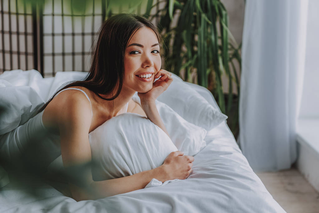 Affascinante donna asiatica guardando la fotocamera sul letto
 - Foto, immagini