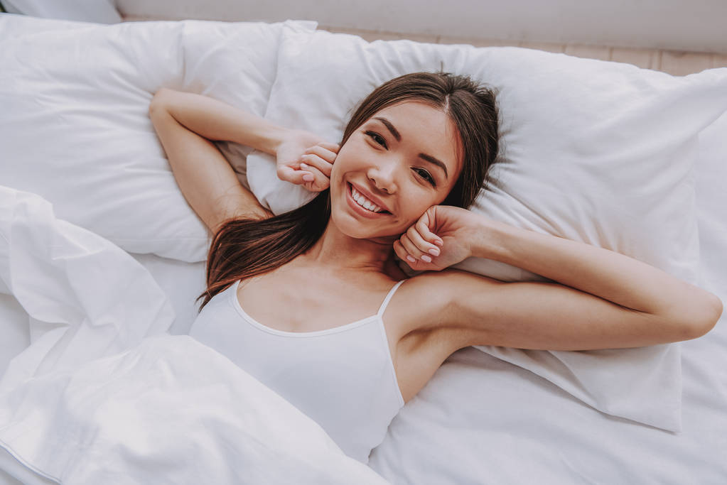 Urocza dziewczyna azjatyckich po śnie, leżąc w łóżku miękkie - Zdjęcie, obraz