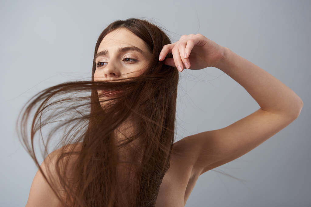 Красива дівчина з довгим прямим волоссям позує на світло-блакитному тлі
 - Фото, зображення
