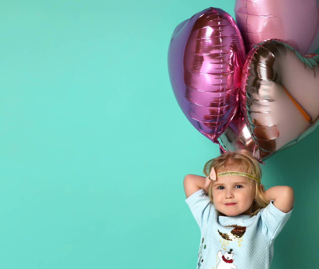 маленька дівчинка розважається з купою рожевих повітряних кульок у формі її серця
. - Фото, зображення