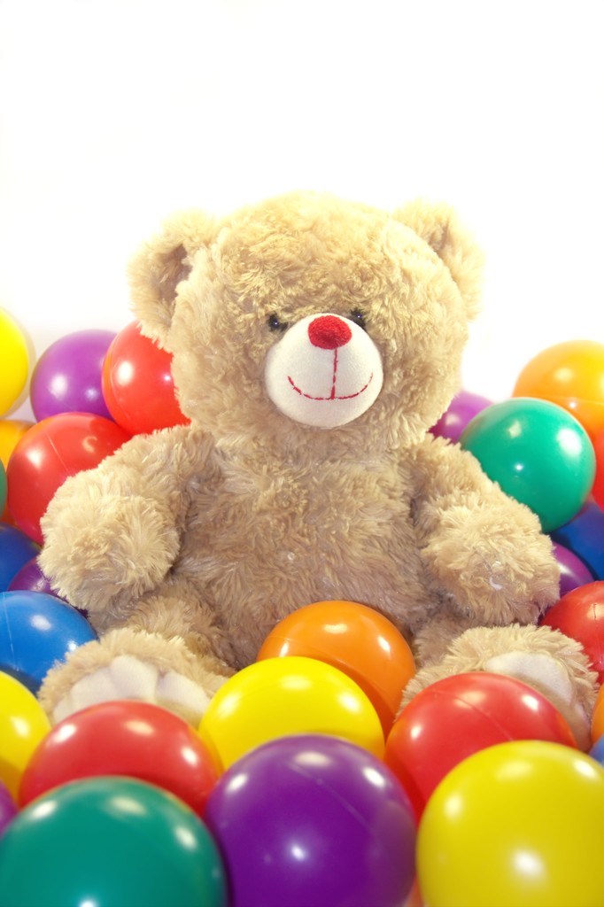 Teddy bear è seduto in palline colorate
 - Foto, immagini
