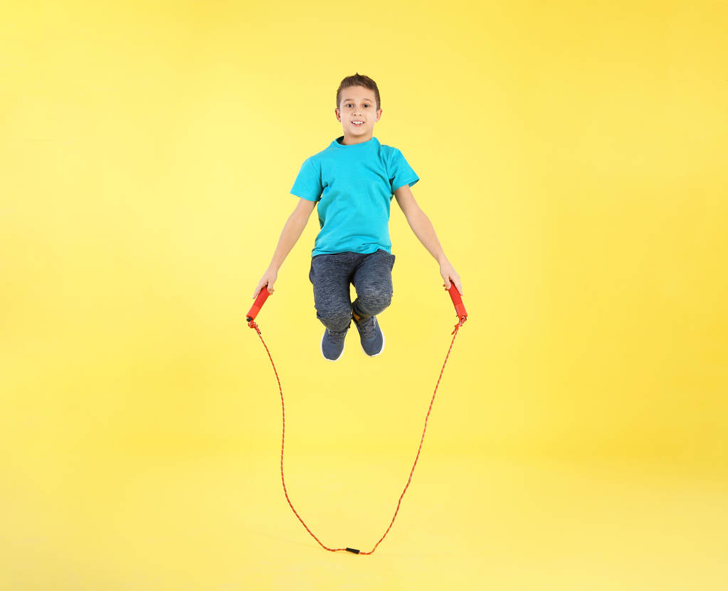 Retrato de comprimento total do menino pulando corda no fundo de cor
 - Foto, Imagem