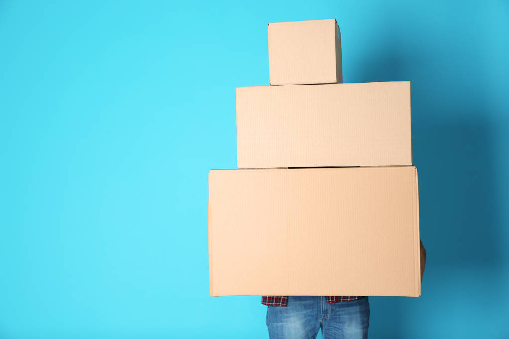 Man with moving boxes on color background. Space for text - Photo, Image