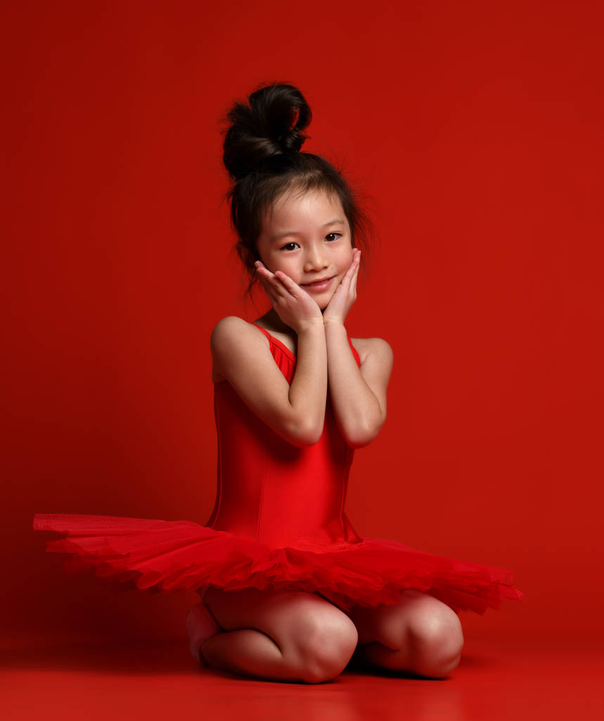 Schattig klein meisje ballerina balletdanser in mooie jurk is dansen op rood  - Foto, afbeelding