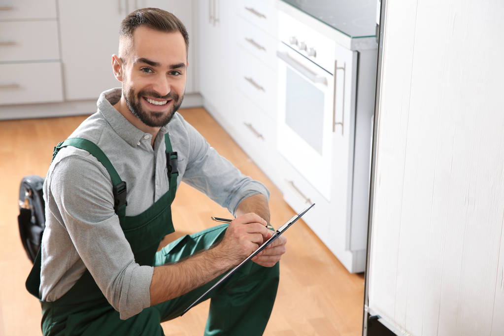 Mutfak bir buzdolabı inceleyerek Pano ile erkek teknisyen - Fotoğraf, Görsel