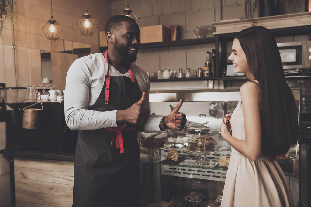 Maschio barista aiuta una ragazza a scegliere un dessert
 - Foto, immagini