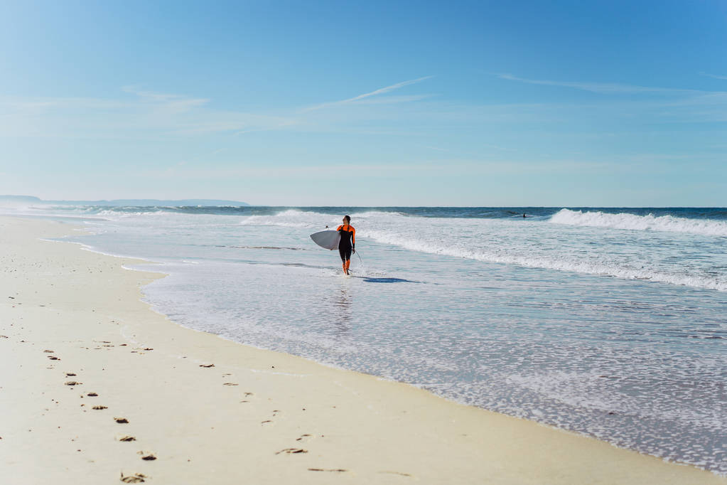 surf girl en la costa del océano en un traje de neopreno con tabla de surf, Nazar, Portugal
. - Foto, Imagen