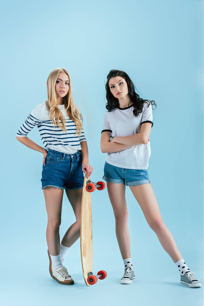 Winsome meisjes poseren met longboard op blauwe achtergrond - Foto, afbeelding