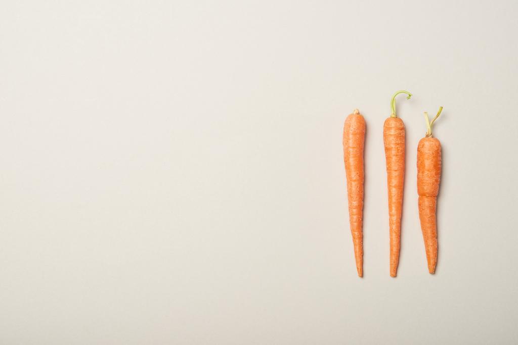 Top näkymä tuoreita porkkanoita harmaalla pohjalla
 - Valokuva, kuva