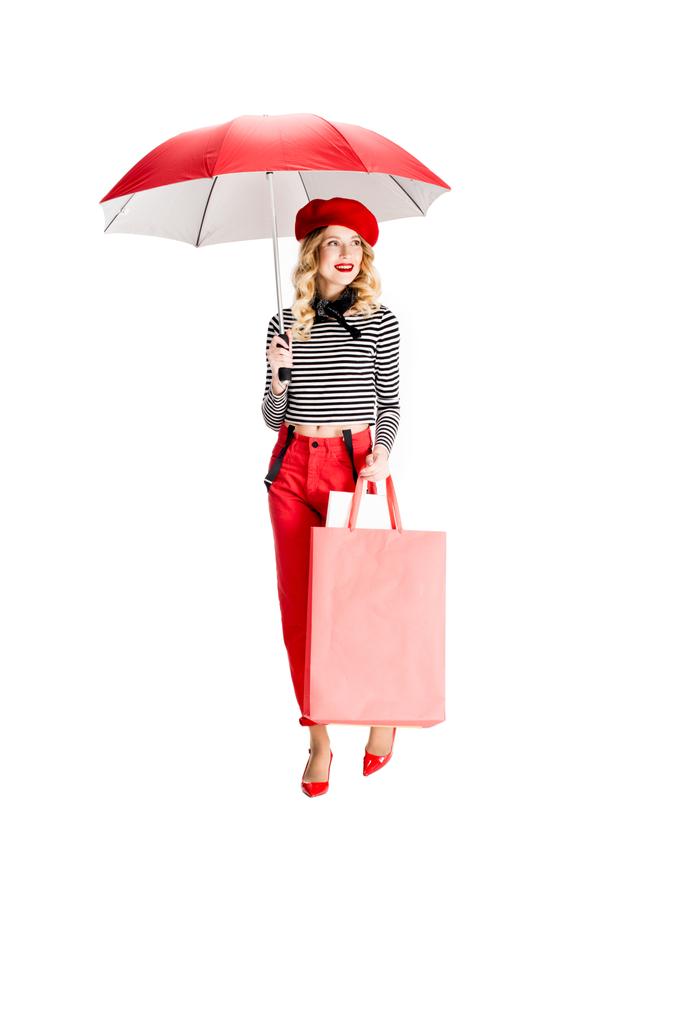 ładna kobieta trzymając czerwony parasol, stojąc z torby na zakupy na białym tle  - Zdjęcie, obraz