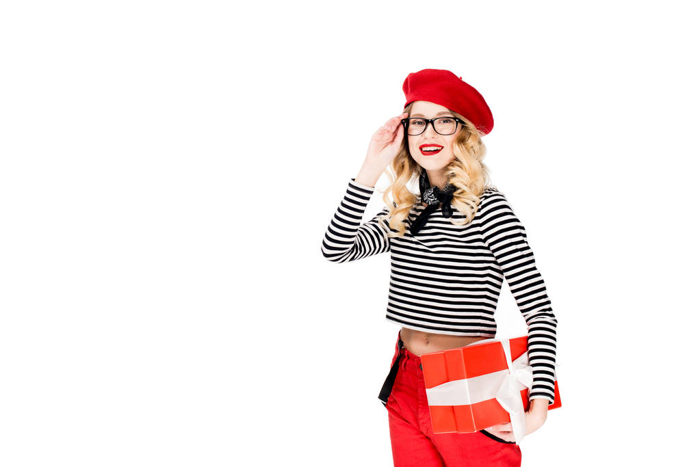 ギフト ボックスが白で隔離を保持している眼鏡と赤のベレー帽で美しい女性  - 写真・画像