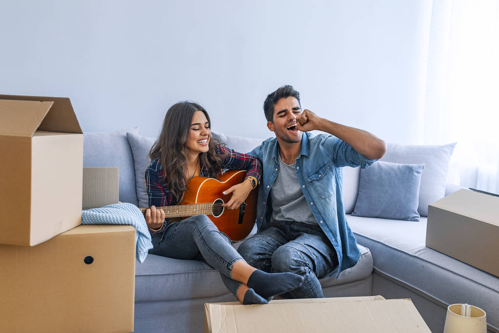 Giovane coppia divertirsi con la chitarra in nuova casa
  - Foto, immagini