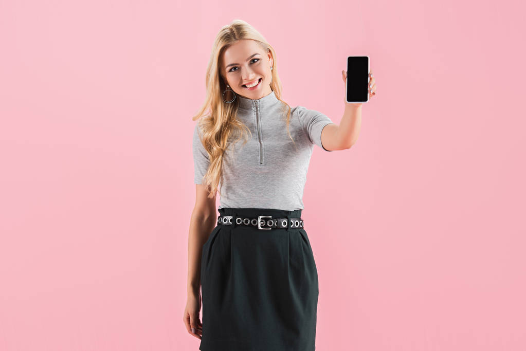 hermosa chica feliz mostrando teléfono inteligente con pantalla en blanco, aislado en rosa
 - Foto, imagen