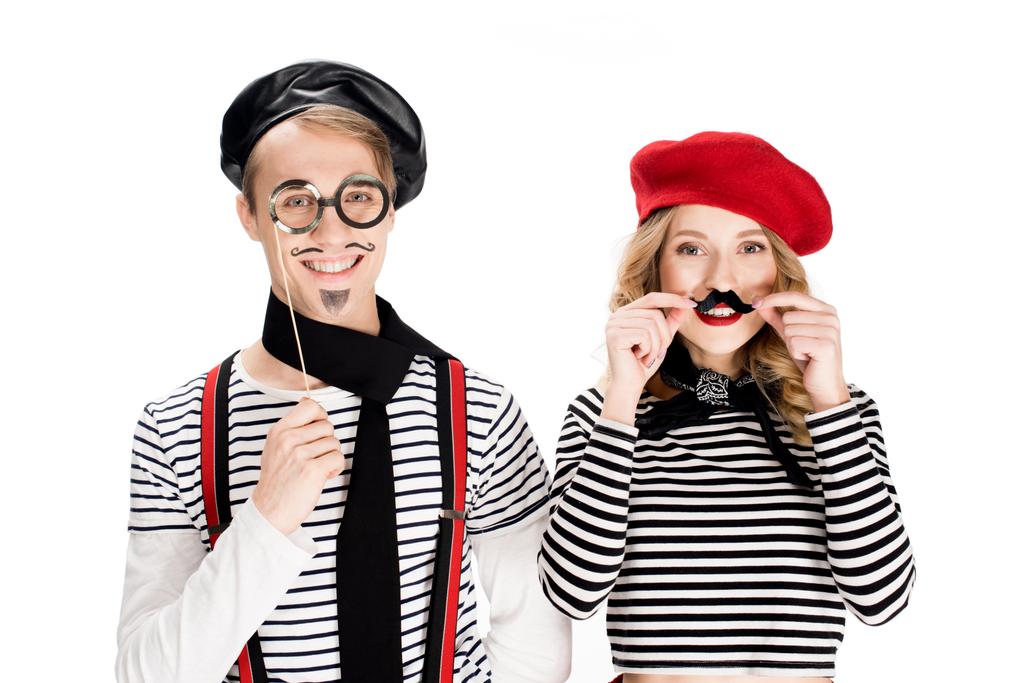 smiling woman holding fake mustache near man with glasses on stick isolated on white  - Photo, Image
