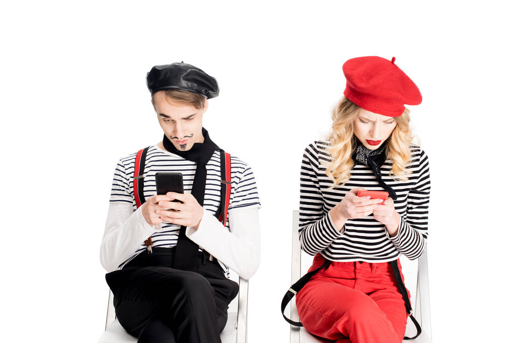 french couple using smartphones while sitting on chairs isolated on white  - Photo, Image