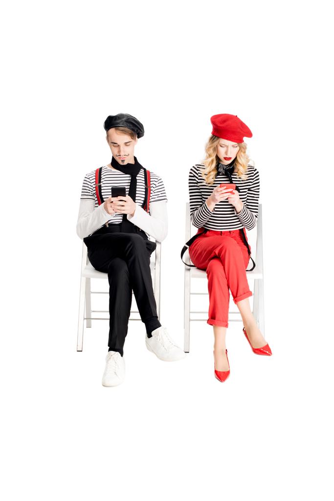 couple français en bérets à l'aide de smartphones assis sur des chaises isolées sur blanc
  - Photo, image