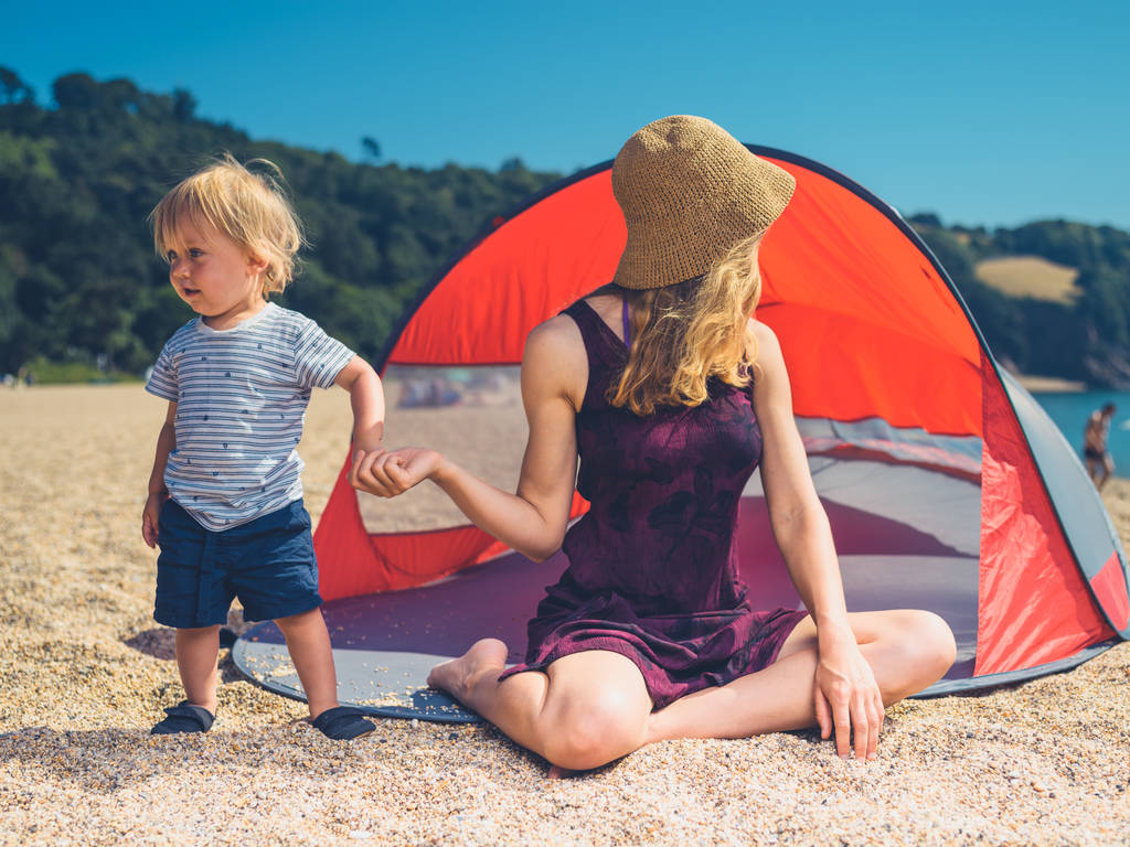 Uma jovem mãe está relaxando em um abrigo de praia com sua criança
 - Foto, Imagem