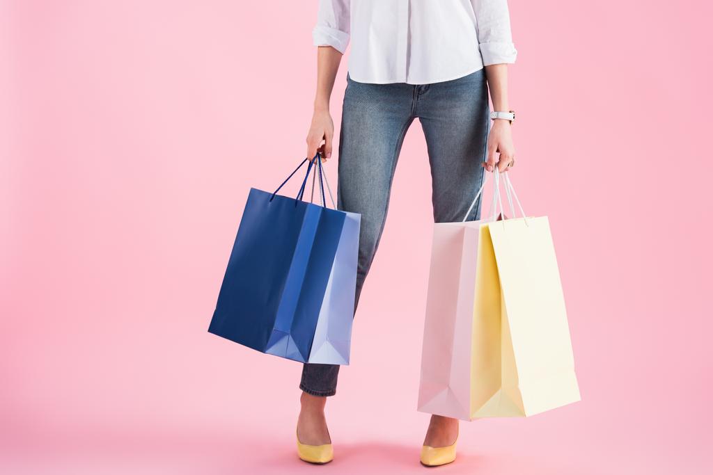 vista cortada de menina segurando sacos de compras, isolado em rosa
 - Foto, Imagem