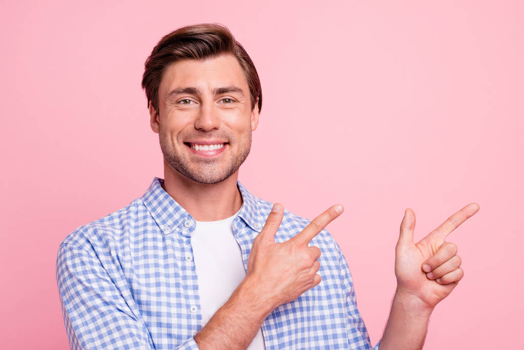 Close up photo of fine brunet smiling glad he him his man arm finger showing to empty space on sale discount wearing casual plaid shirt white t-shirt outfit isolated on pale rose background - Photo, Image