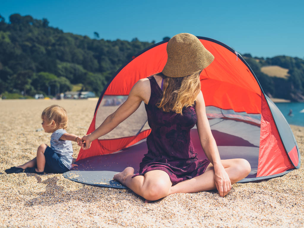 Une jeune mère se relaxe dans un abri de plage avec son tout-petit
 - Photo, image