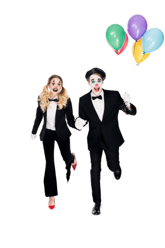 fröhliches Clownspaar, das mit Heliumballons auf weißem Grund läuft  - Foto, Bild