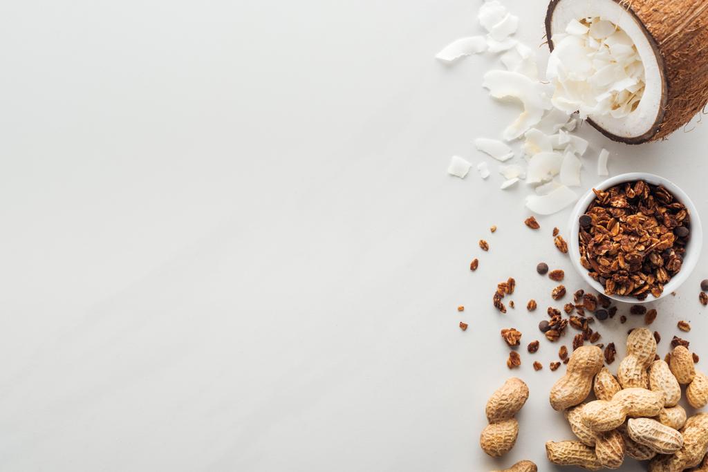 top view of granola, peanuts and coconut with flakes on white background with copy space - Photo, Image