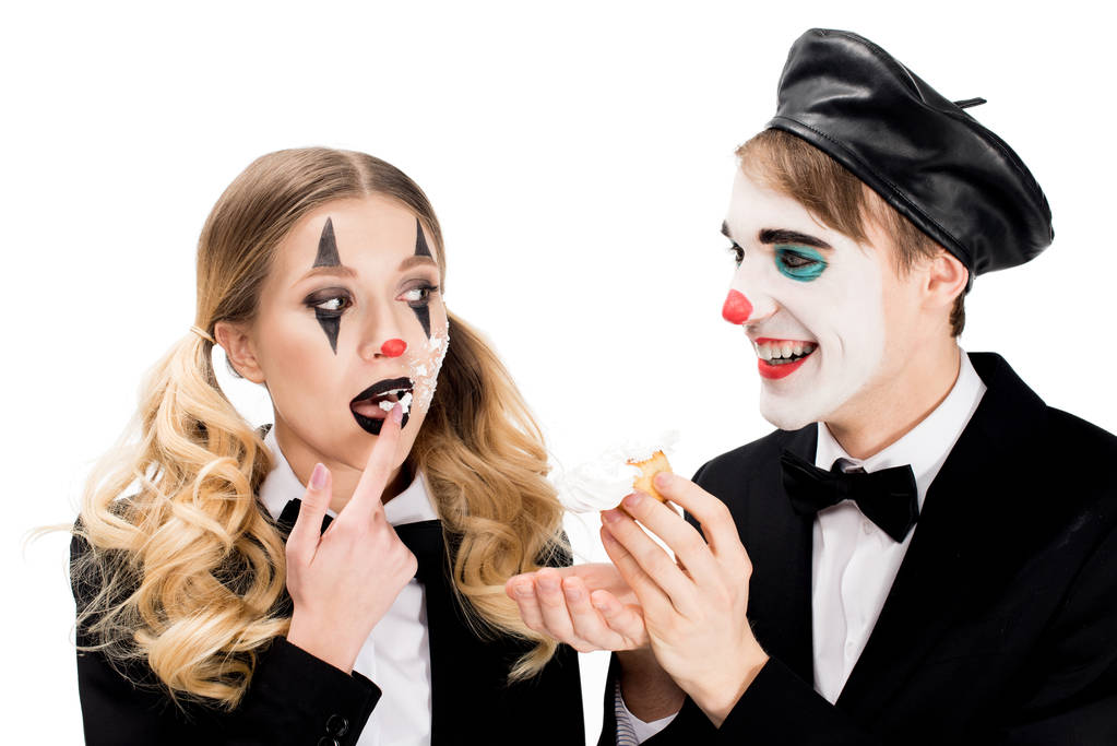 lachende clown kijken vrouw met cupcake op gezicht likken van zoete vinger geïsoleerd op wit  - Foto, afbeelding