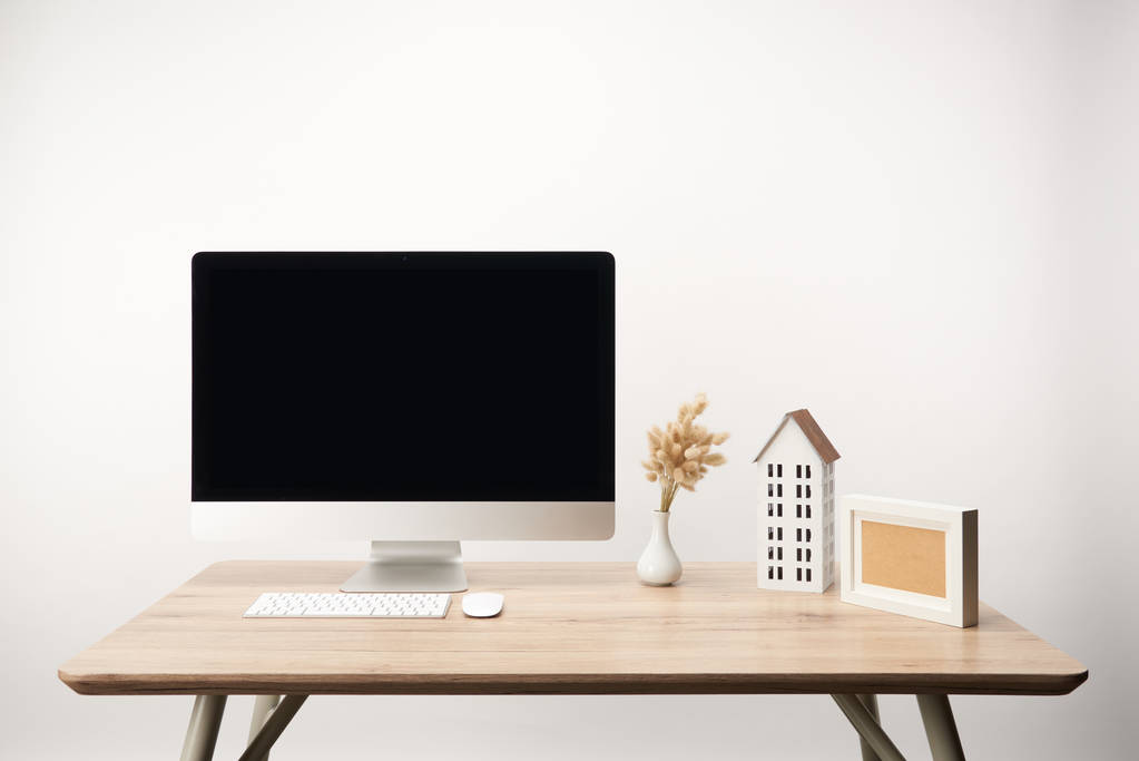werkplek met huis model, droge bloemen en desktop computer met kopie ruimte geïsoleerd op wit - Foto, afbeelding