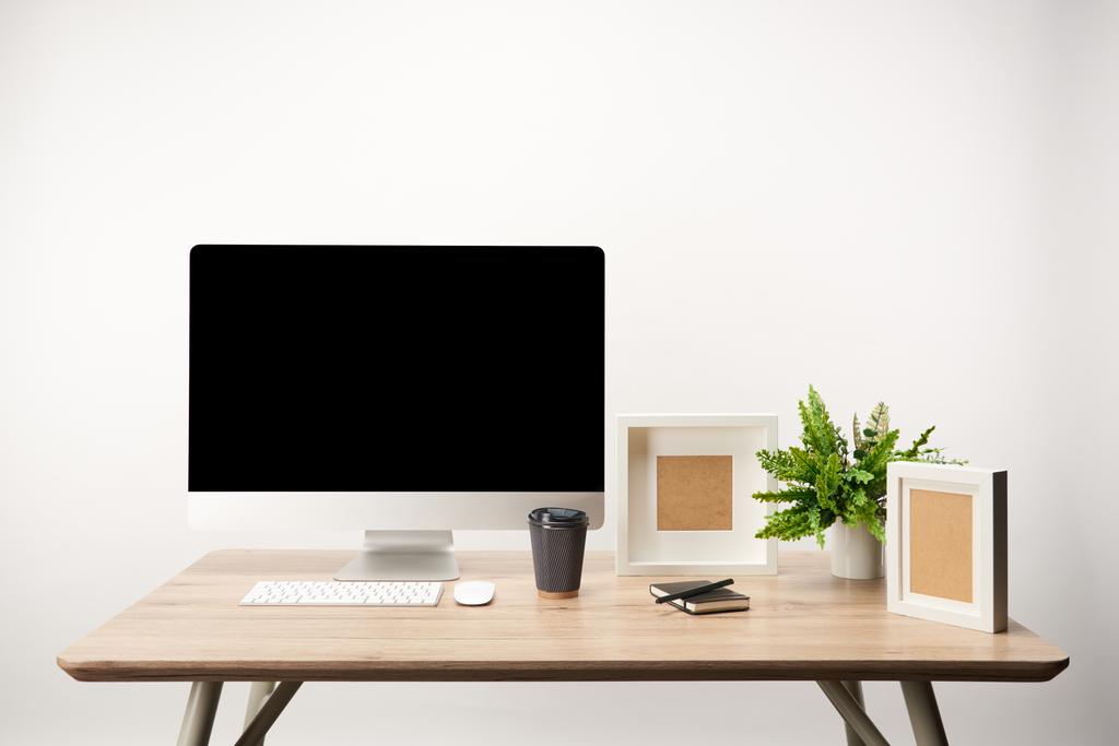 workplace with coffee to go, photo frames, plant and desktop computer with copy space isolated on white - Photo, Image
