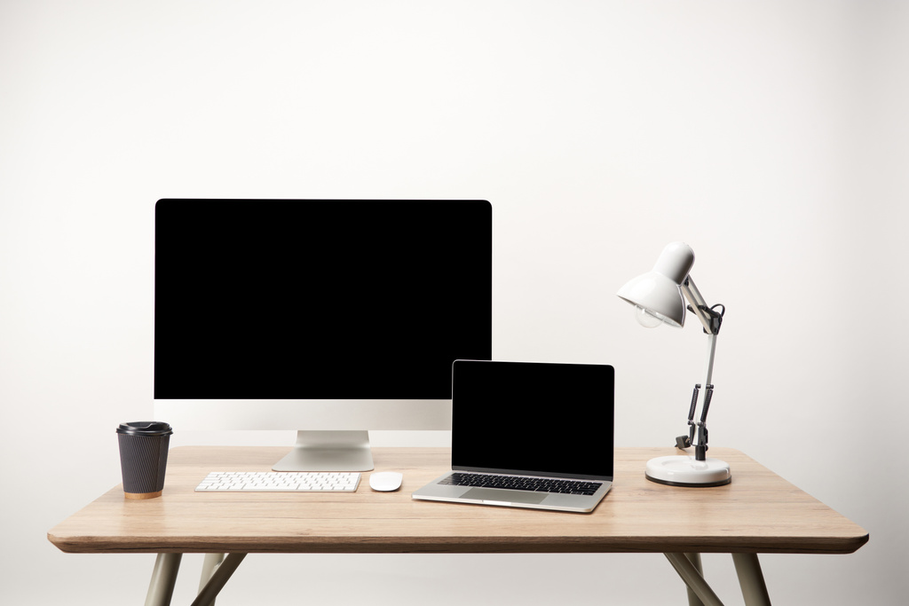 στο χώρο εργασίας με φωτιστικό, καφέ να πάτε, υπολογιστή γραφείου και lap-top με χώρο αντίγραφο που απομονώνονται σε λευκό - Φωτογραφία, εικόνα