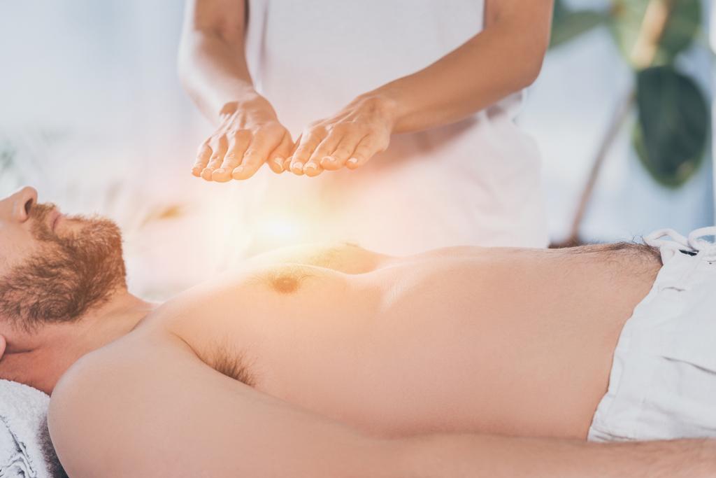 cropped shot of bearded man receiving reiki treatment on bare chest - Photo, Image