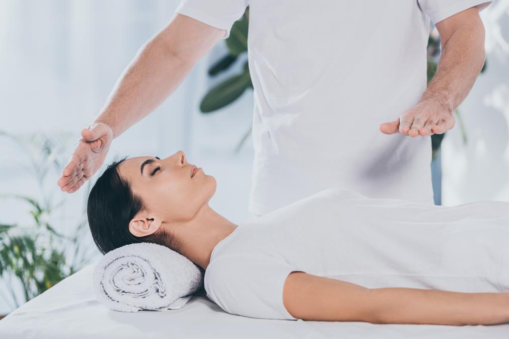 cropped shot of calm young woman receiving reiki treatment from male healer - Photo, Image