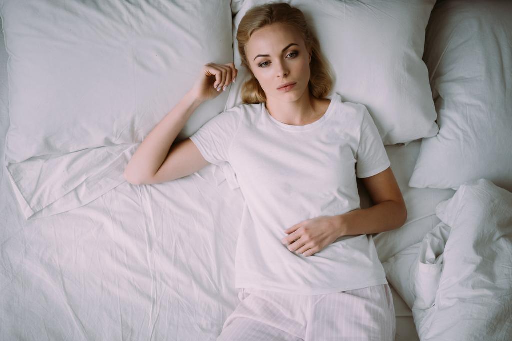 vista superior de la mujer molesta en pijama acostada en la cama en casa
 - Foto, Imagen