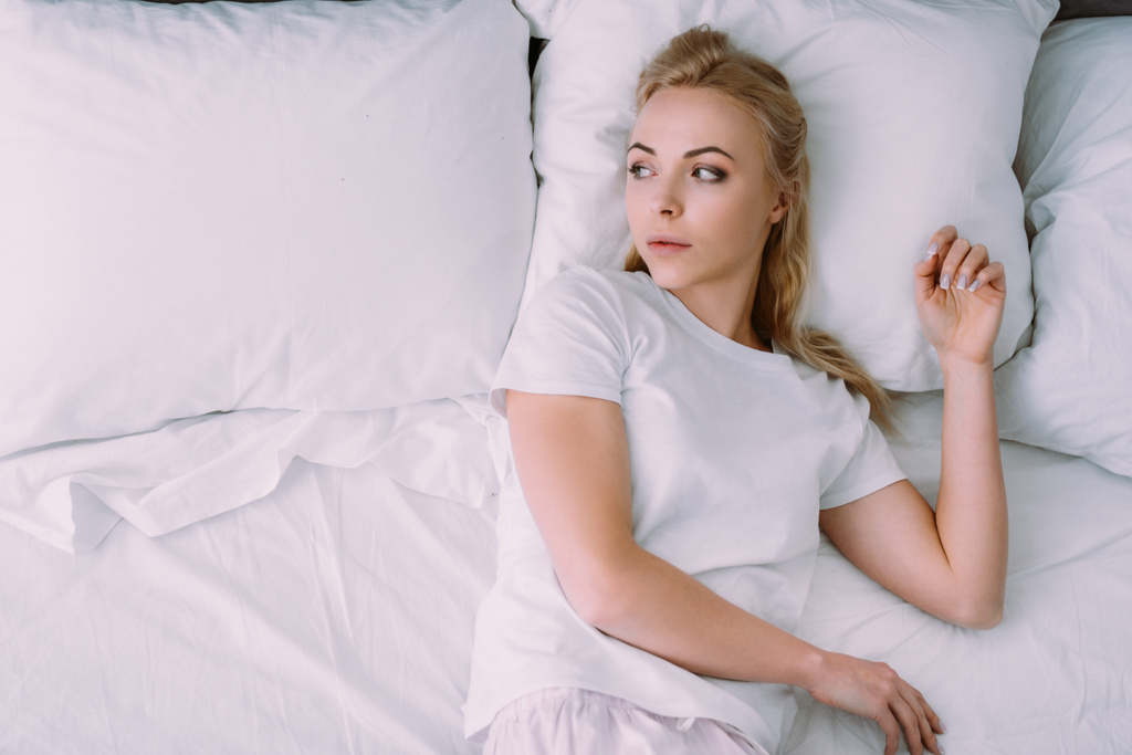 mulher deprimida de pijama branco deitado na cama com espaço de cópia
 - Foto, Imagem