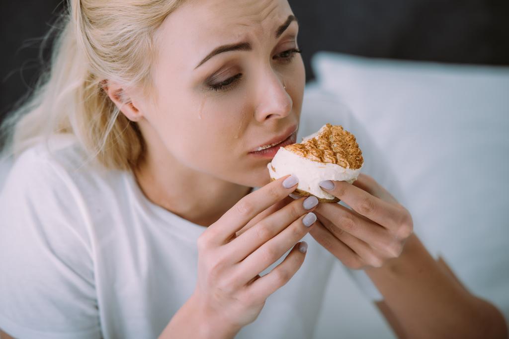 valikoiva painopiste masentunut nainen pyjamassa syöminen kakku sängyssä yksin
 - Valokuva, kuva