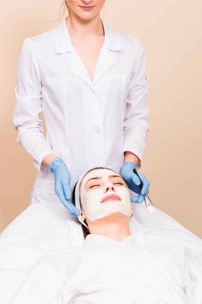 美容師美容院で顔に化粧品のマスクを持つ女性の後ろに立って - 写真・画像