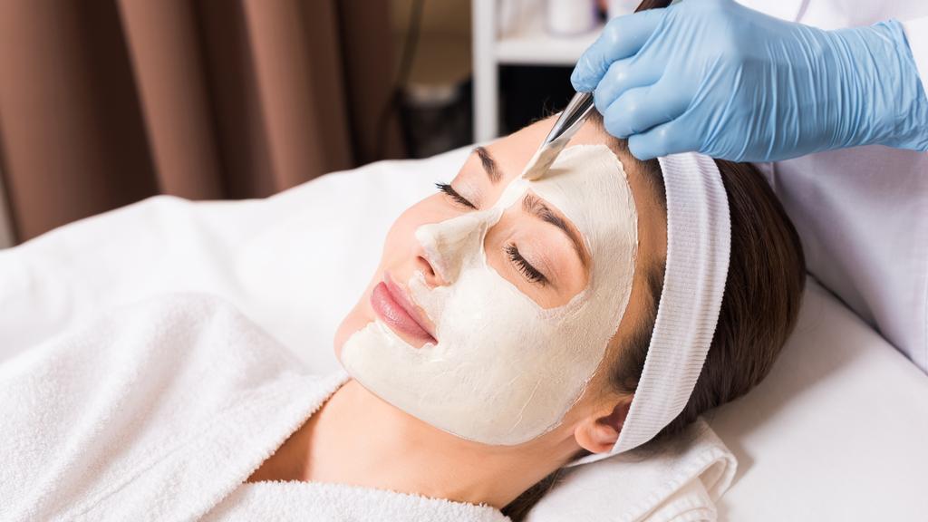 esthéticienne appliquant masque cosmétique à la femme sur demi-visage avec pinceau cosmétique au salon de beauté
 - Photo, image