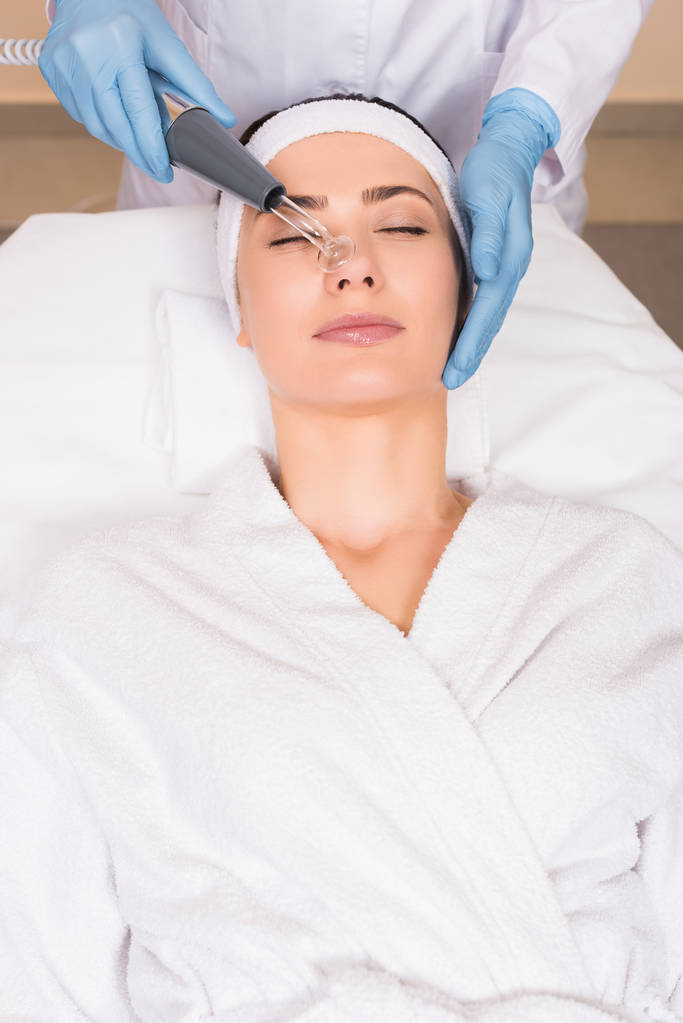 Kosmetikerin macht Darsonvalisierung der Nase einer Frau im Schönheitssalon - Foto, Bild