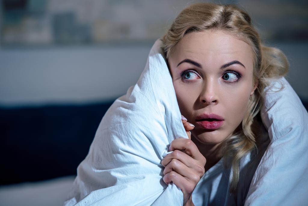 selektiver Fokus der verängstigten Frau, die in eine Decke gehüllt im Schlafzimmer wegschaut - Foto, Bild