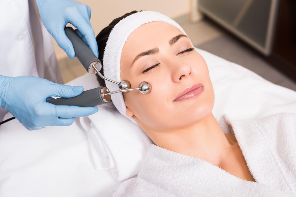 femme couché esthéticienne wile faire massage levant sur le visage avec l'équipement au salon de beauté
 - Photo, image