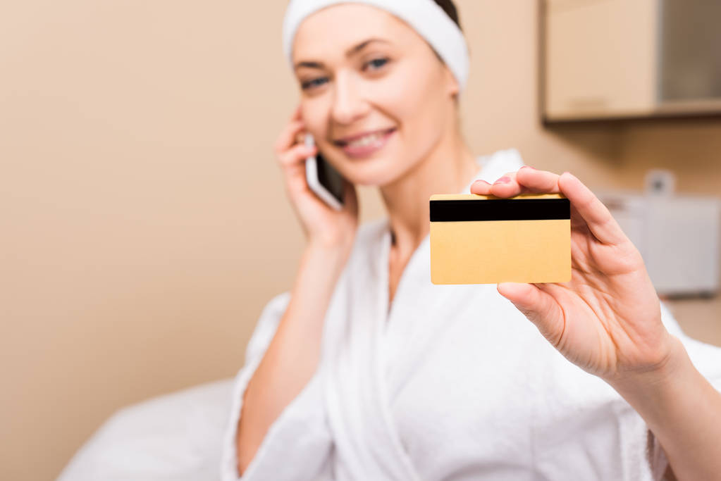 вибірковий фокус кредитної картки в руці жінки, сидячи і розмовляючи на смартфоні в салоні краси
 - Фото, зображення