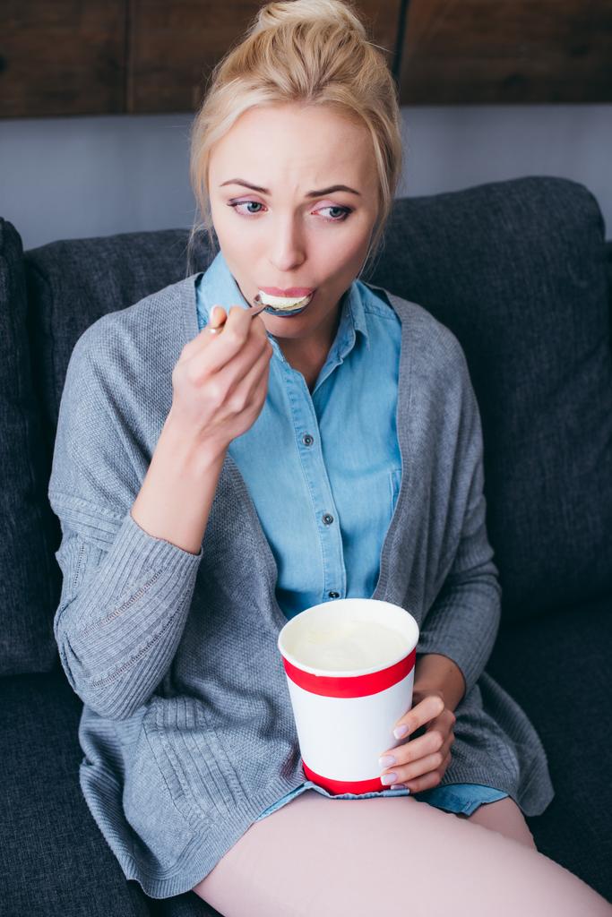 smutna kobieta jedzenie lodów podczas siitng na kanapie w domu sam - Zdjęcie, obraz