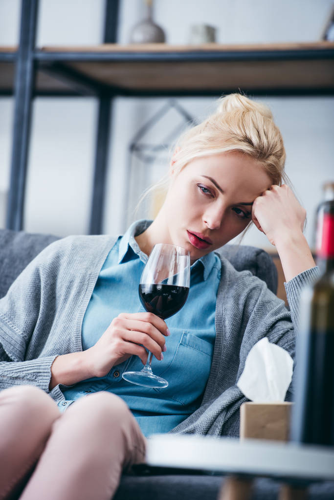 mujer molesta sentada con vaso de vino tinto y caja de pañuelos en casa
 - Foto, imagen