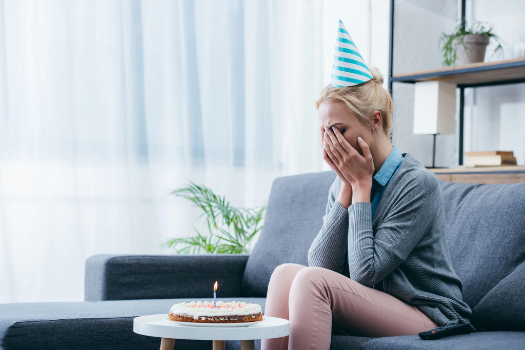 mujer molesta en sombrero de fiesta llorando mientras celebra cumpleaños en casa solo
 - Foto, Imagen