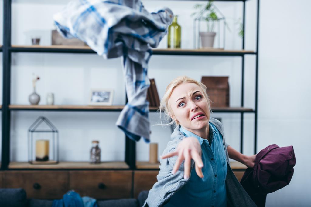aggressiivinen nainen heittää vaatteita olohuoneessa jälkeen hajottaa kanssa poikaystävä
 - Valokuva, kuva