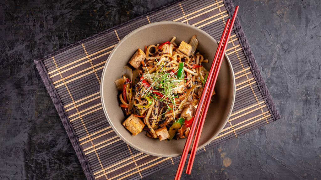 日本料理のコンセプトです。鶏、焼き野菜と豆腐うなぎの中華麺。竹マットの上の板のレストランではアジア料理を提供します。コピー スペース平面図 - 写真・画像