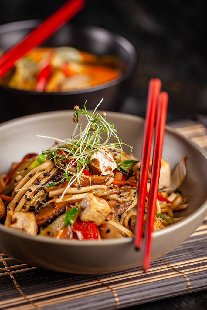 Japon mutfağı kavramı. Çin Eriştesi tavuk, ızgara sebzeler ve tofu unagi sos ile. Bir plaka üzerinde bir bambu hasır Restaurant'ta Asya yemekleri sunan. Üstten görünüm, kopya alanı - Fotoğraf, Görsel